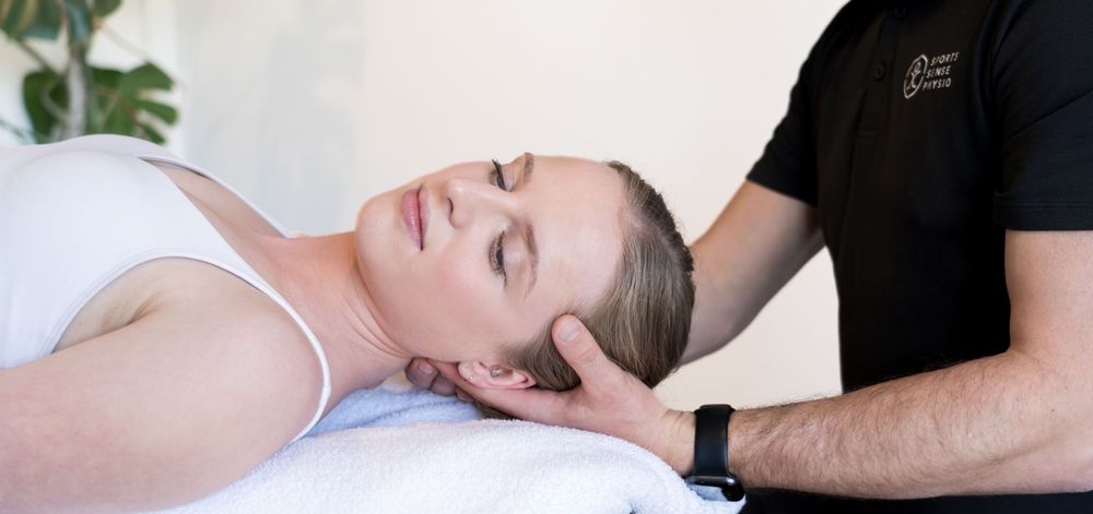 Patient receives therapeutic neck massage treatment on massage table.