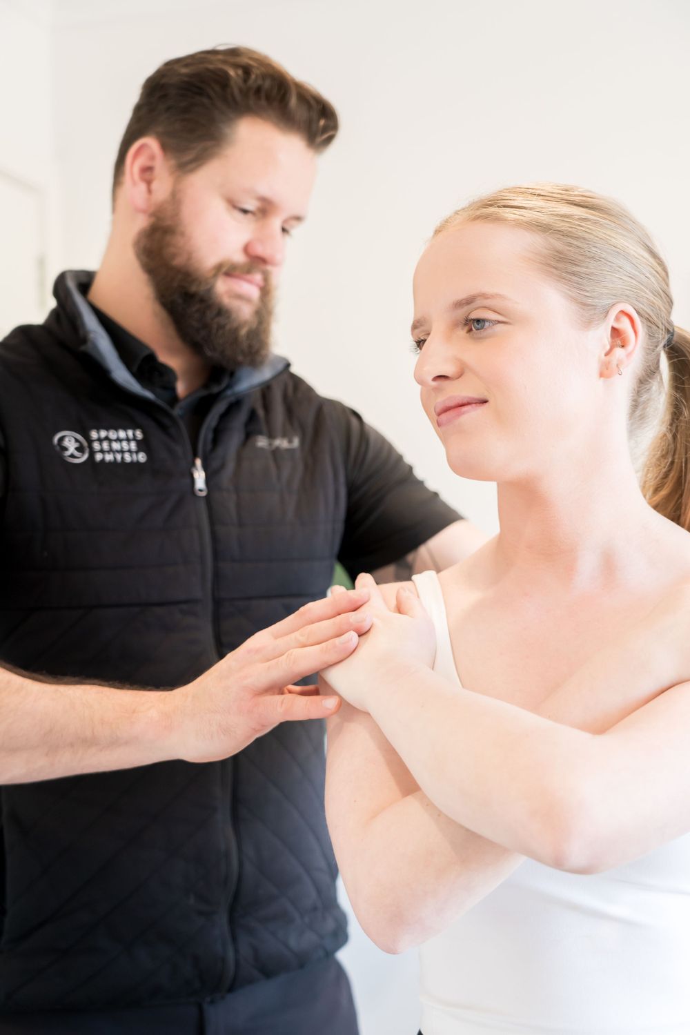 Physical therapist performs gentle arm movement assessment on patient during treatment session.