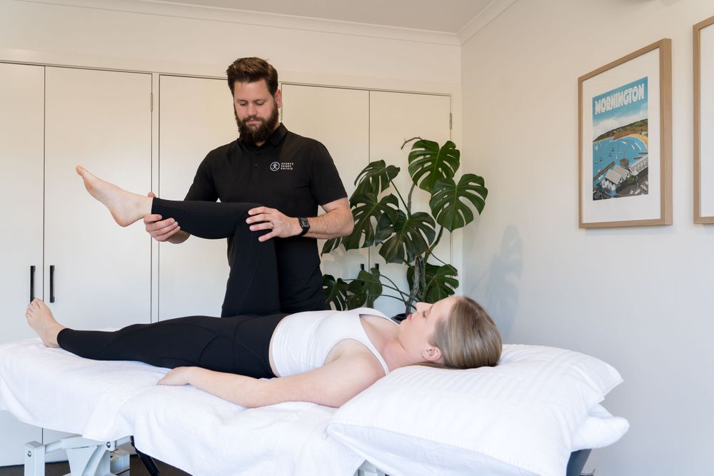 Physiotherapist demonstrating treatment technique with patient on massage table.