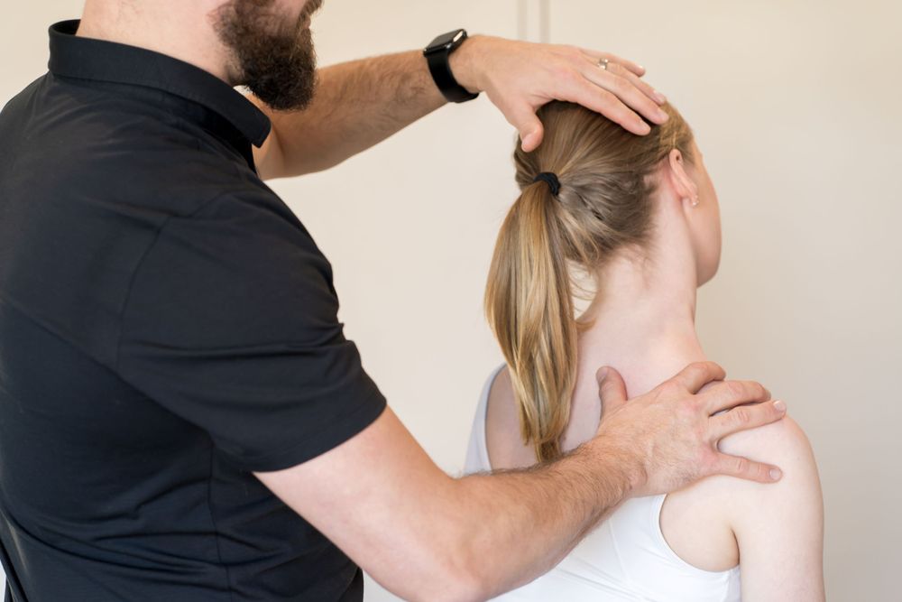 Therapist providing neck and shoulder treatment during physiotherapy session.