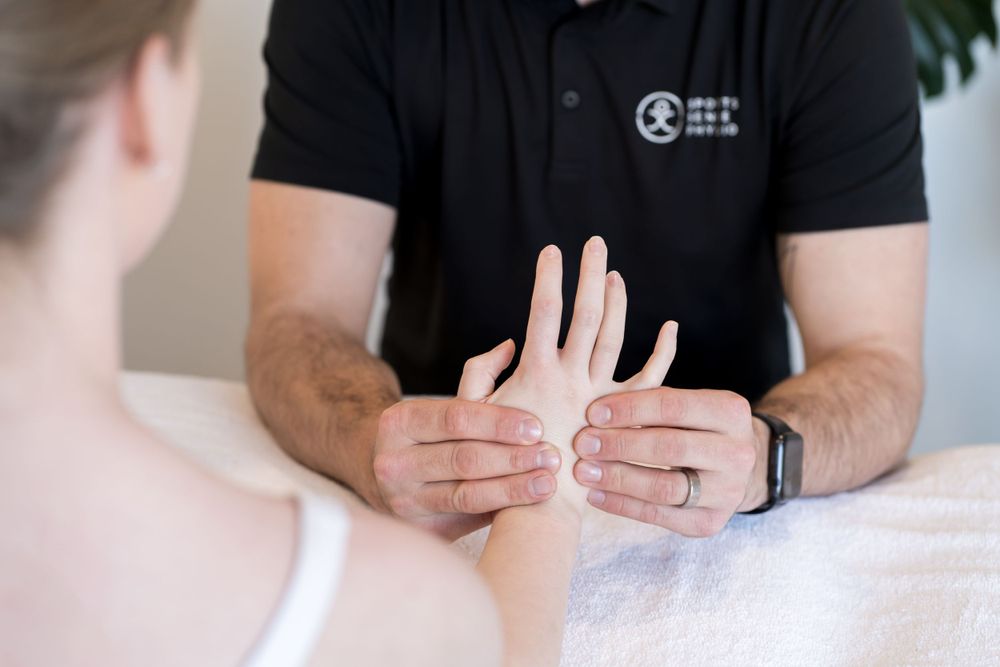 Physiotherapist examining patient's hand and wrist during treatment session.