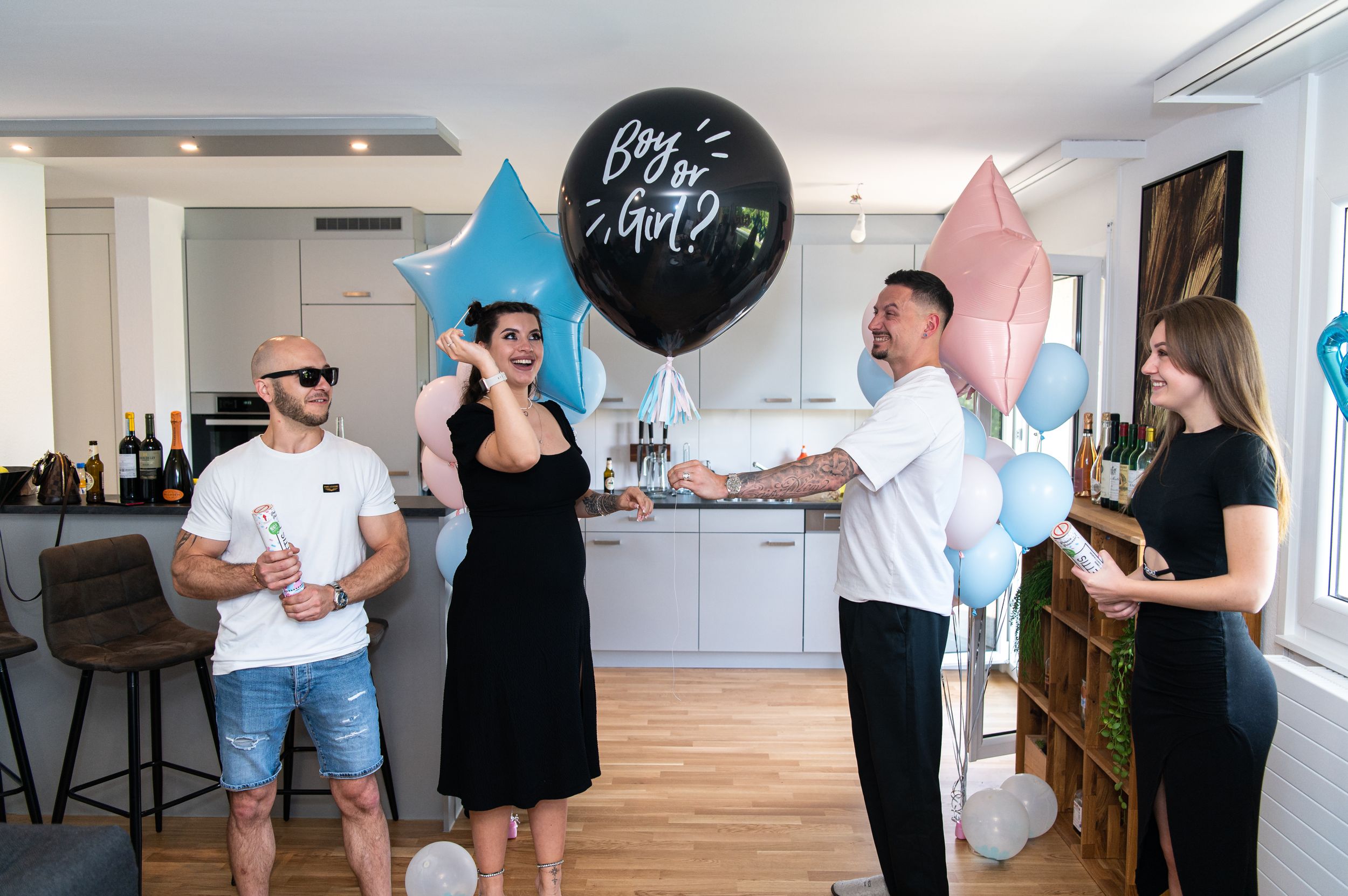Gender reveal party setup in modern home with blue and pink balloon decorations.