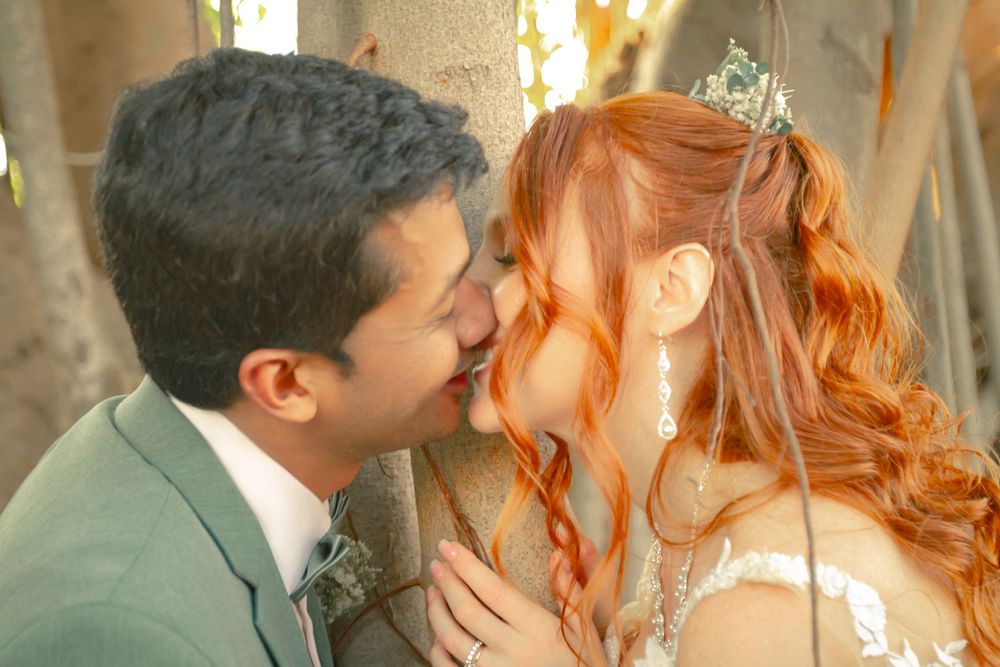 Newlywed couple sharing a tender kiss at their wedding, with the bride wearing a tiara and white dress.