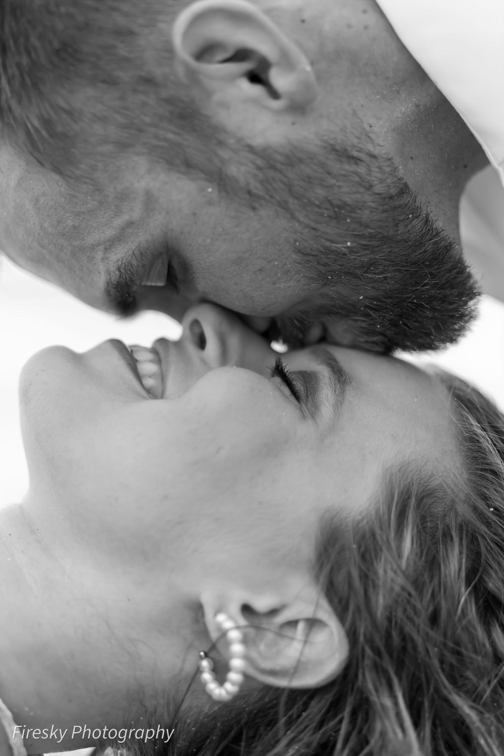 Close-up black and white intimate portrait of a couple about to kiss with sparkly earring detail.