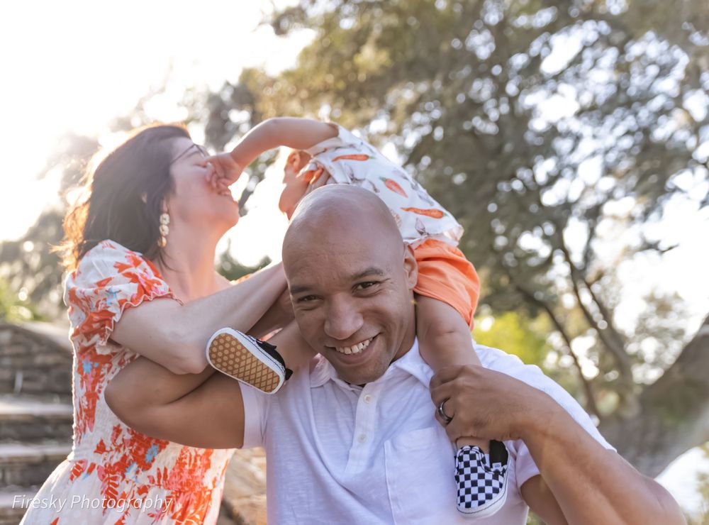 Family enjoying playful outdoor moment together during sunset photoshoot.