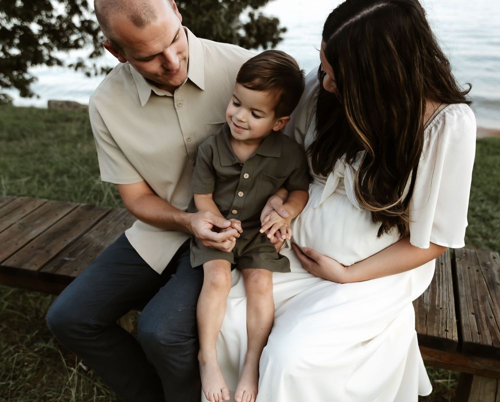 Family sharing a tender moment together while sitting on a wooden deck near the water.