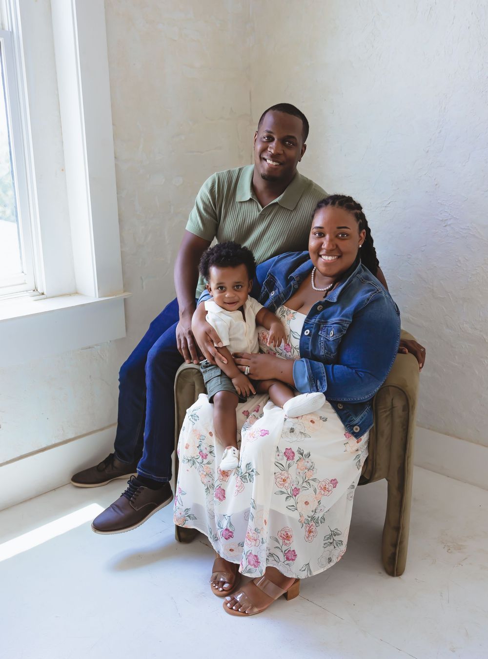 Heartwarming family portrait of three people sitting together in a bright white room.