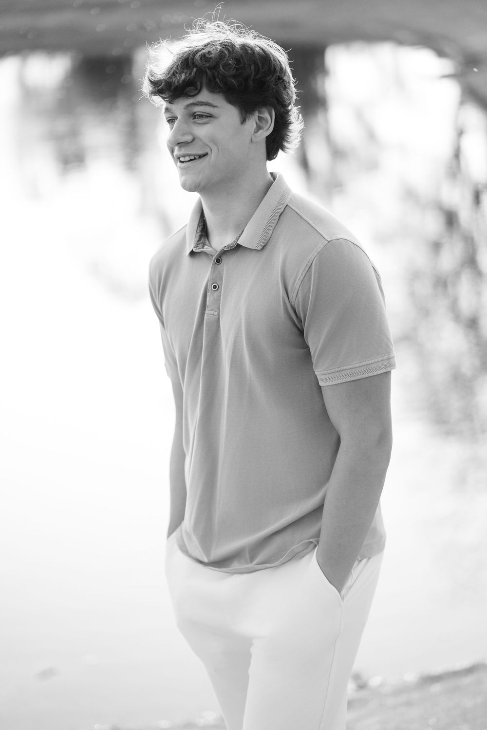 Black and white portrait series showing a person in a polo shirt smiling and looking to the side in natural light.
