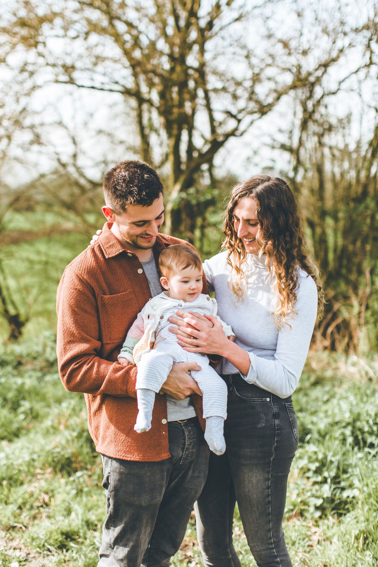 Young family spending time together outdoors with their baby in autumn setting.