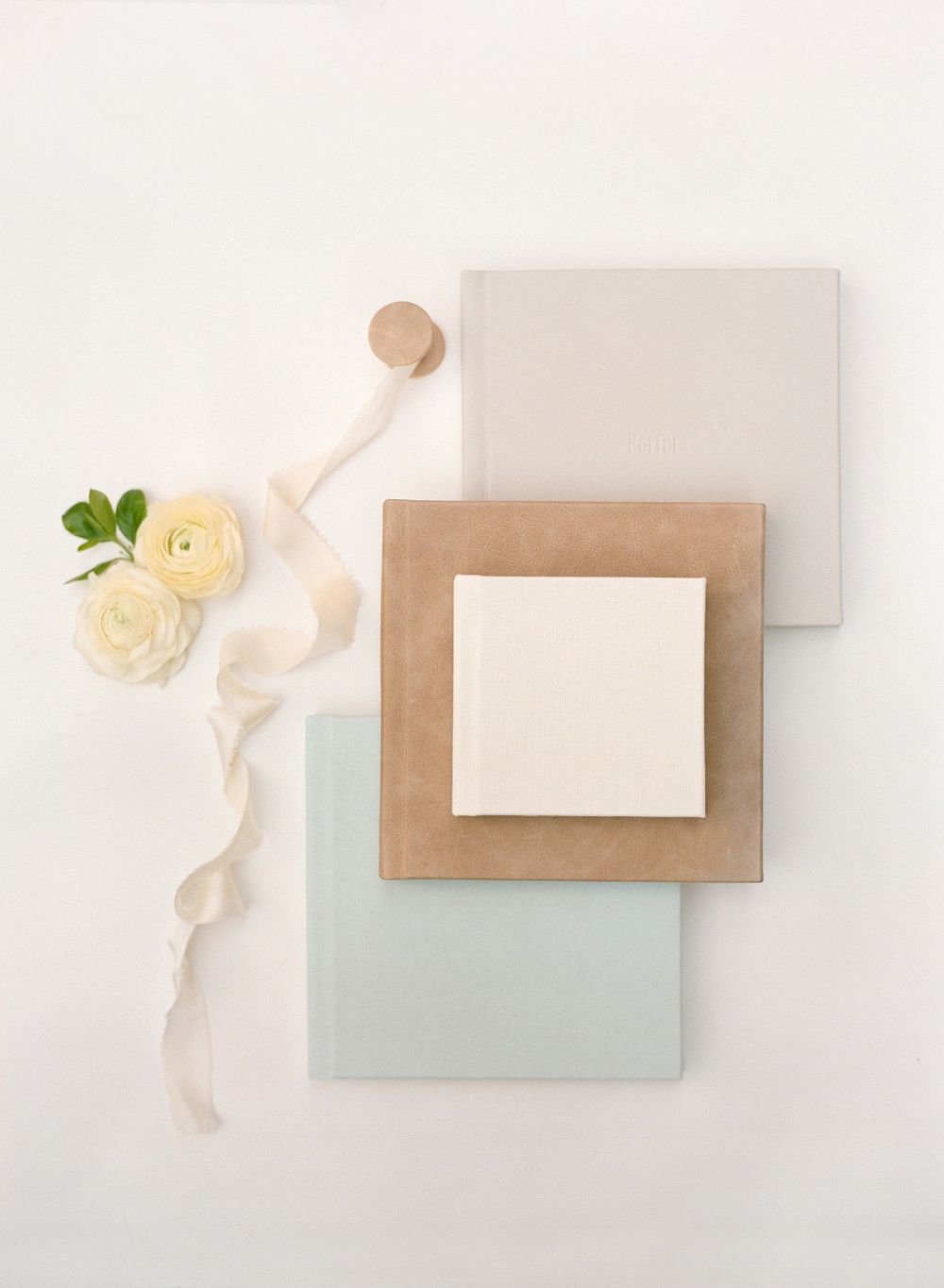 Minimalist flat lay of paper samples with cream ribbon and yellow ranunculus flowers.