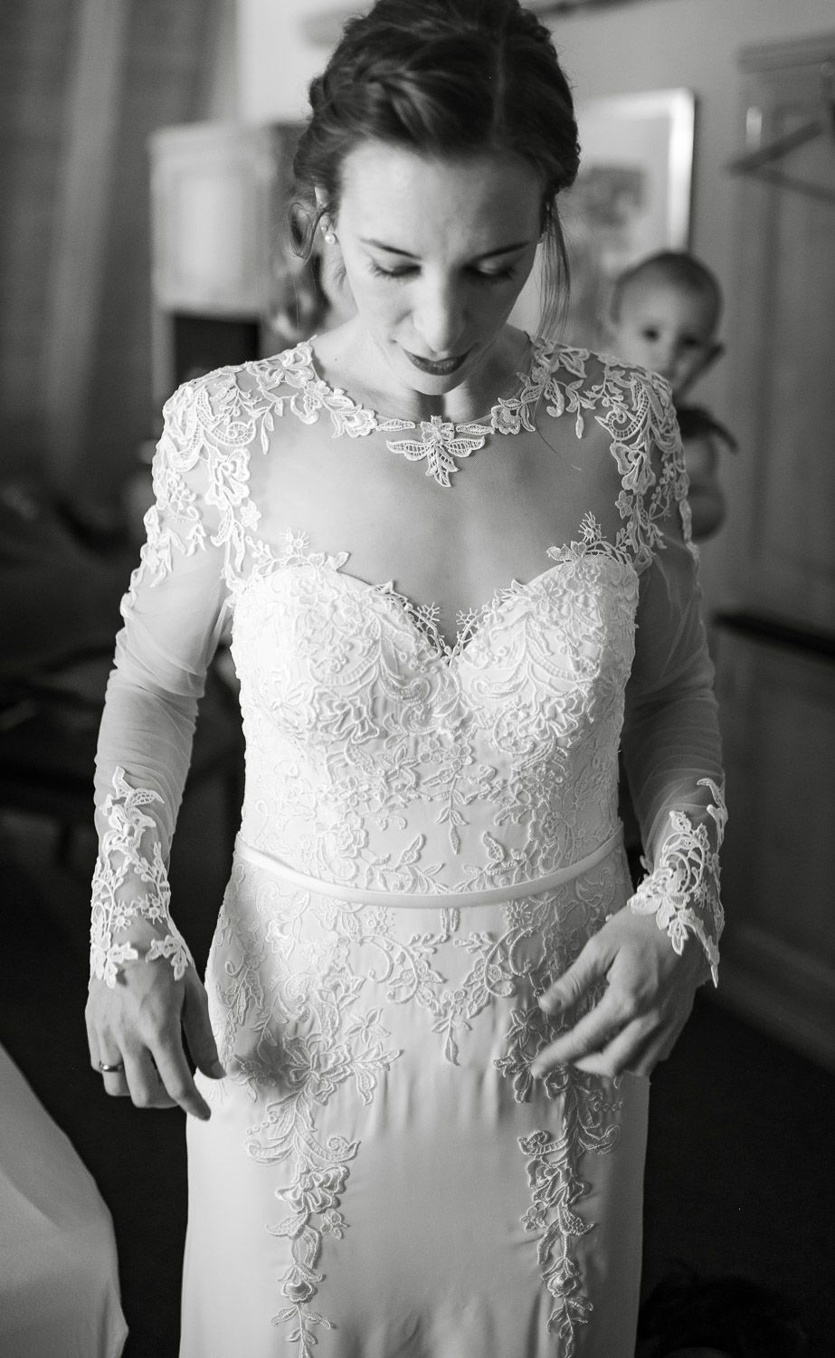 Bride in a fitted lace wedding gown with long sleeves and sweetheart neckline in black and white.