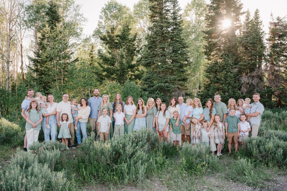 Large group photo of people in coordinated light colors gathered outdoors during golden hour.