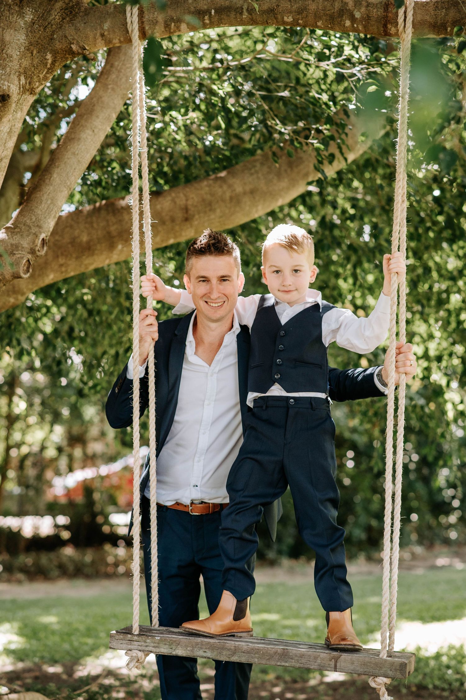 A heartwarming moment on a rustic wooden swing under a leafy tree.