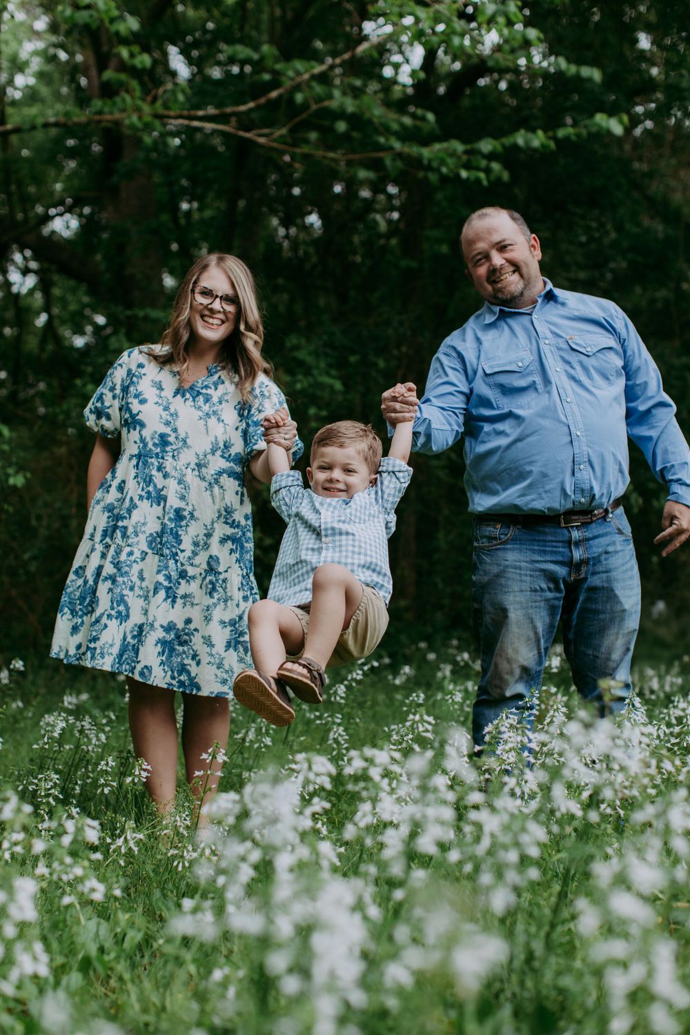 A family enjoying a playful moment together in a flowering meadow during springtime.