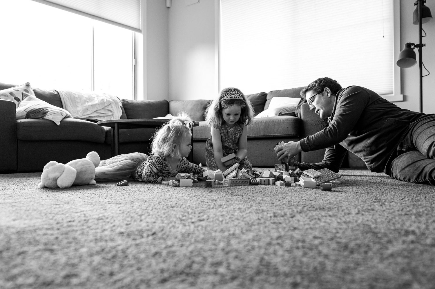 A black and white photo of family playtime with toys on the living room floor.