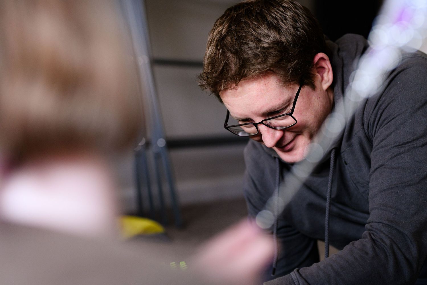 Person in glasses smiles while playing on the floor during playtime.