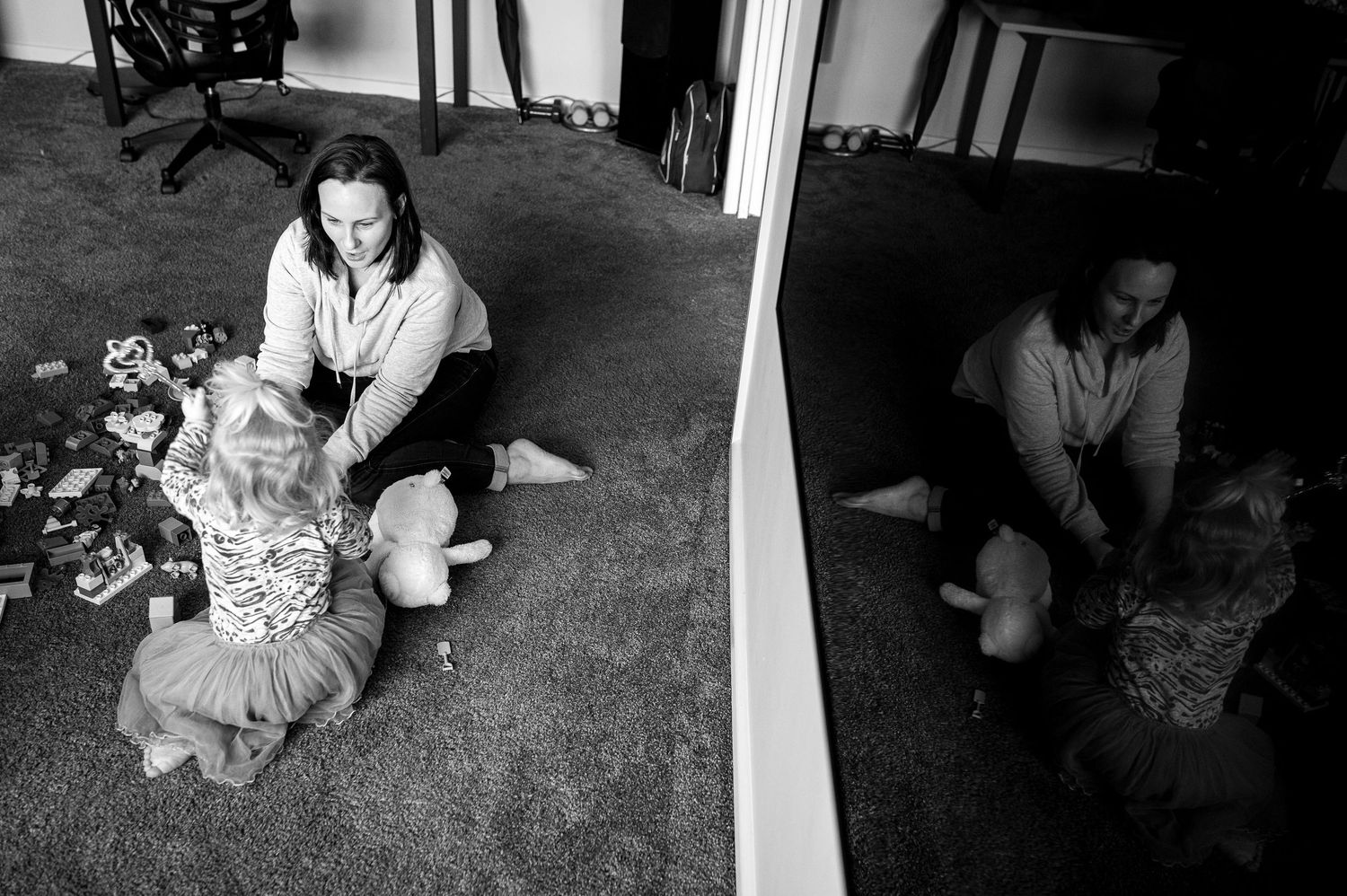 Family playing together with toys on the carpet in black and white photography.