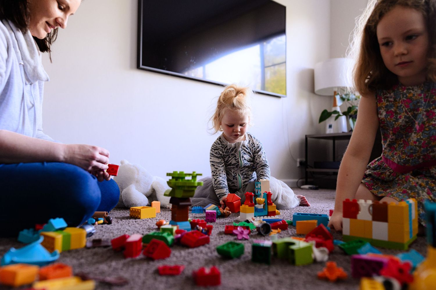 Family playing together with colorful building blocks on the floor.