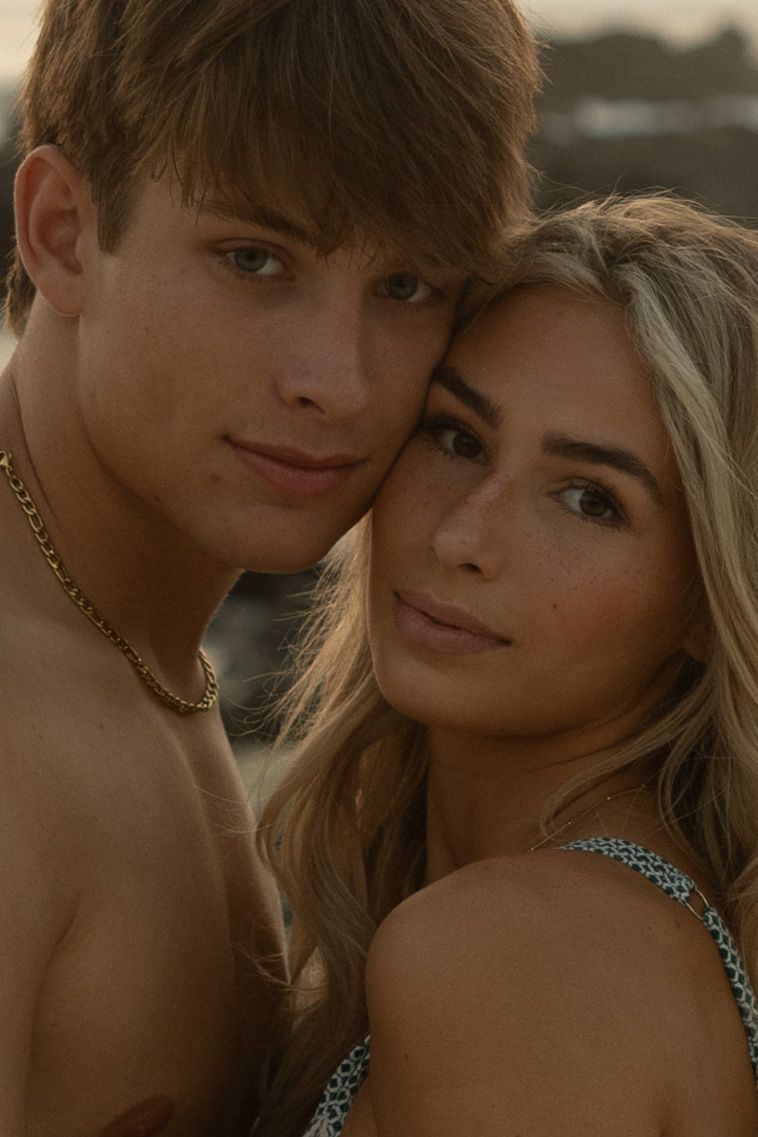 A romantic portrait of a young couple posing together at sunset with soft lighting and natural makeup.