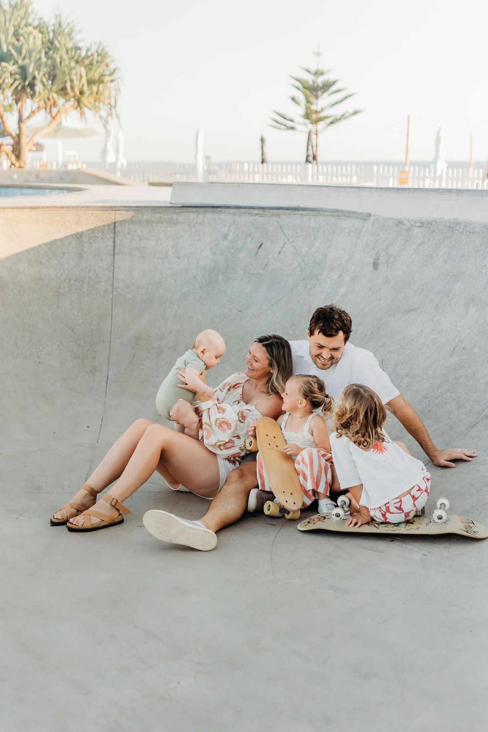 Mum, dad and kids in the skate bowl at their family session, looking on at their little brother playing. Relaxed and candid.