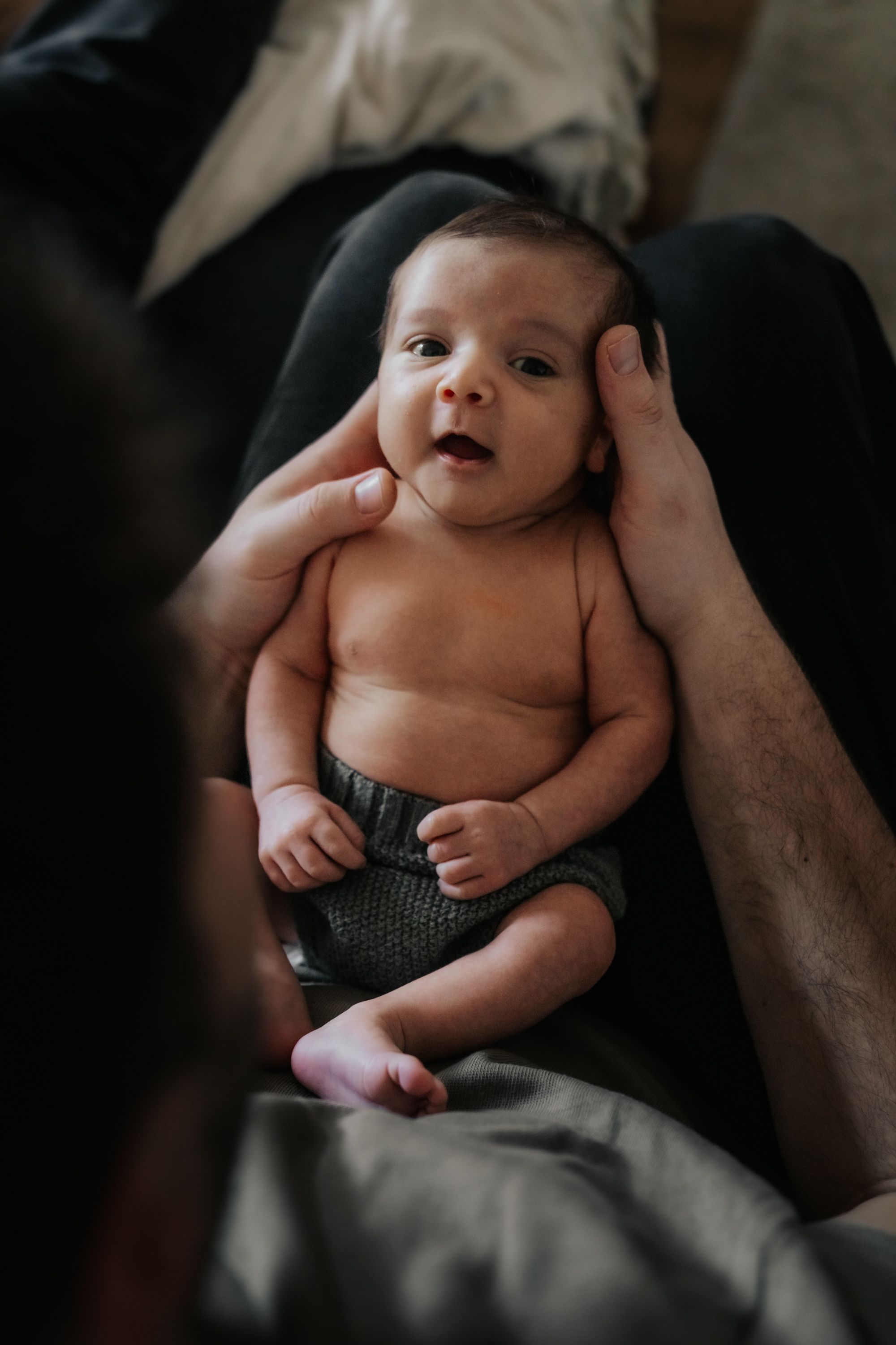 A series of intimate black and white photos showing a smiling baby lying on soft blankets.