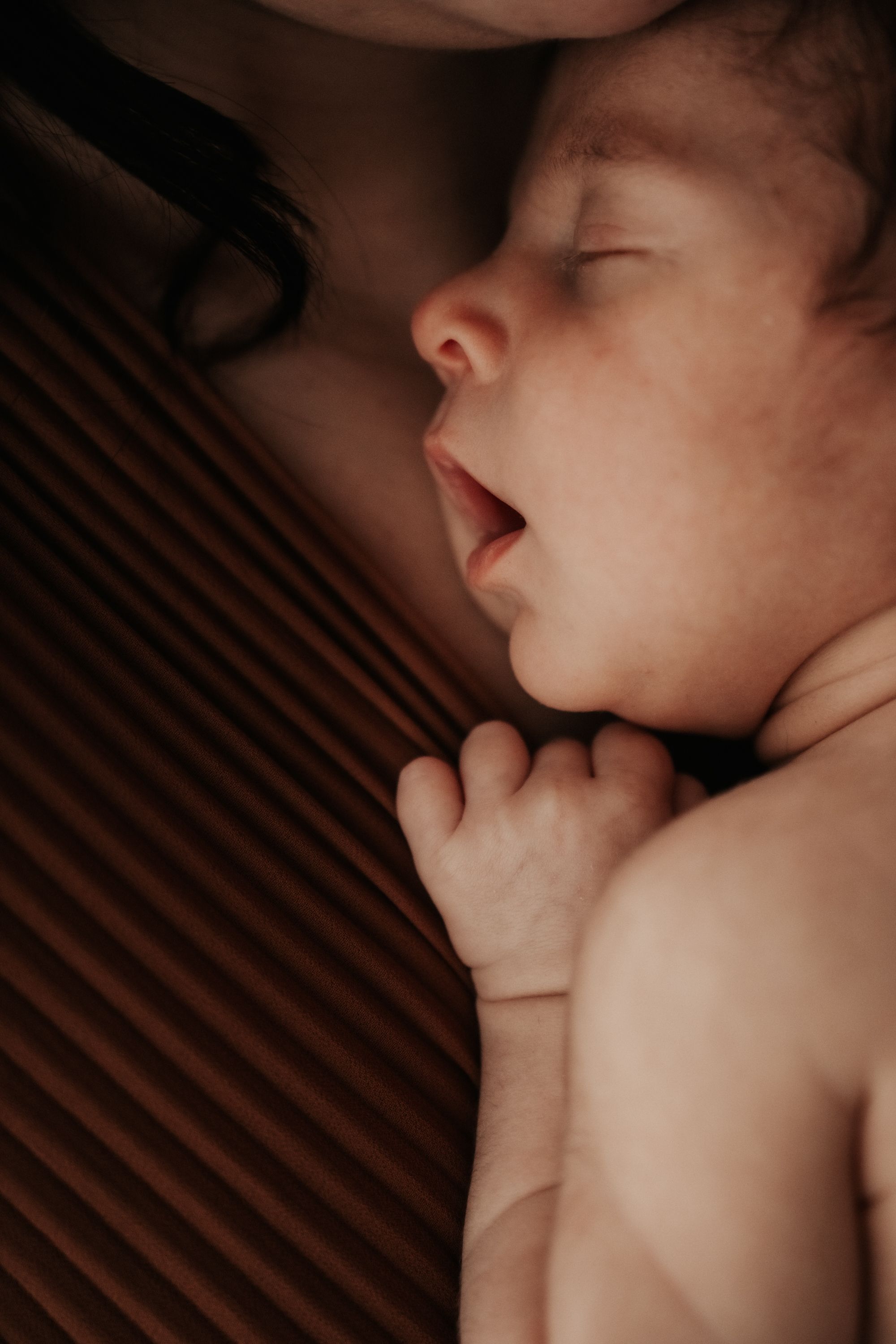 A sleeping baby rests peacefully with tiny fingers curled near their face in a series of intimate close-up shots.
