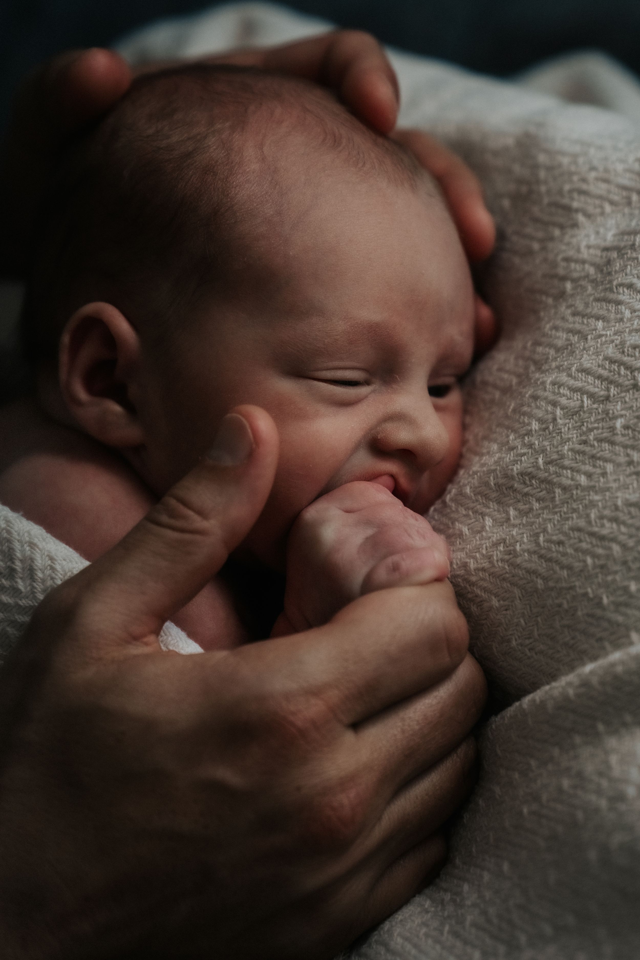 A sleeping baby rests peacefully against soft textured fabric in a series of intimate close-up shots.
