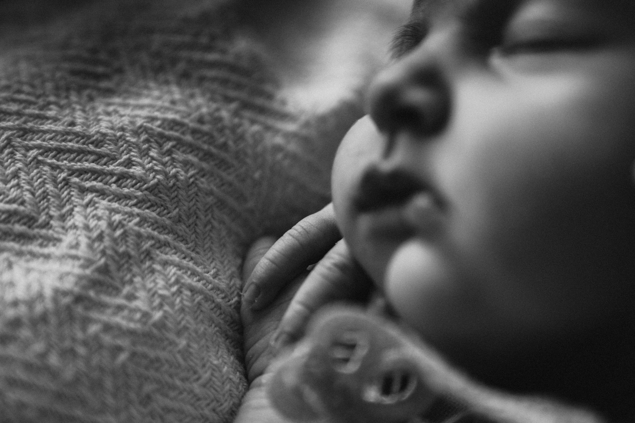 A peaceful black and white macro photograph captures an infant sleeping peacefully on textured fabric.