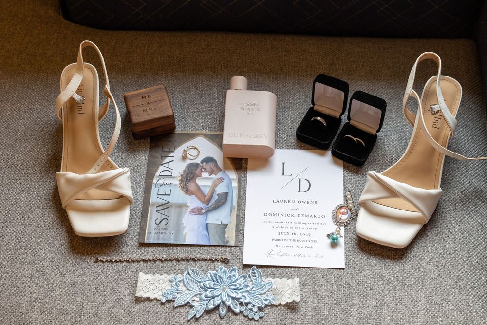 Wedding flat lay featuring bridal heels, rings, invitation, save the date, and accessories.