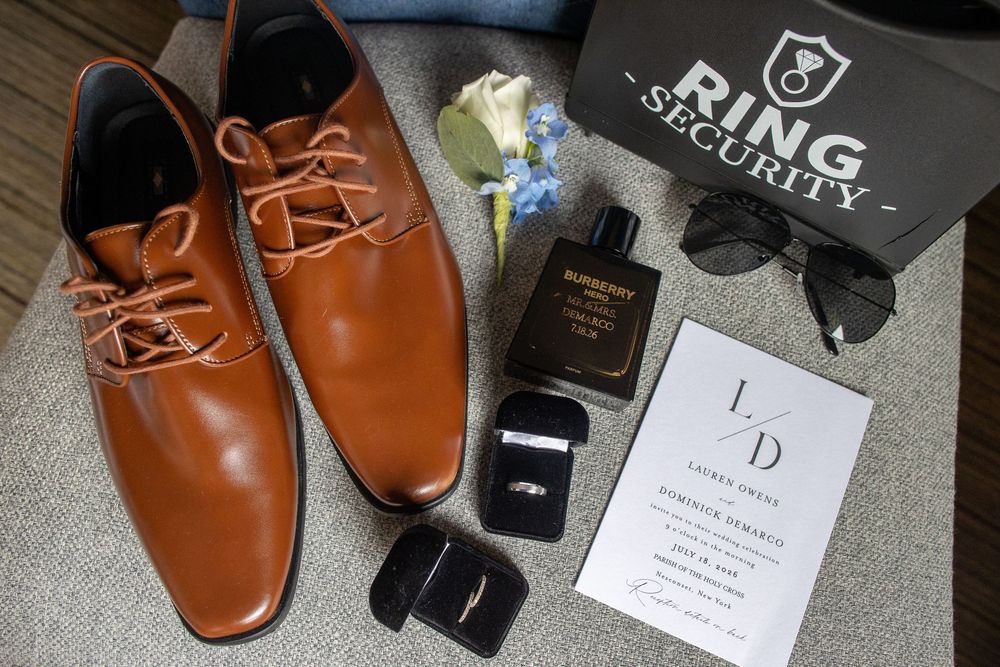 Groom wedding flat lay featuring tan dress shoes, cologne, ring box, boutonniere, and Ring Security bag.