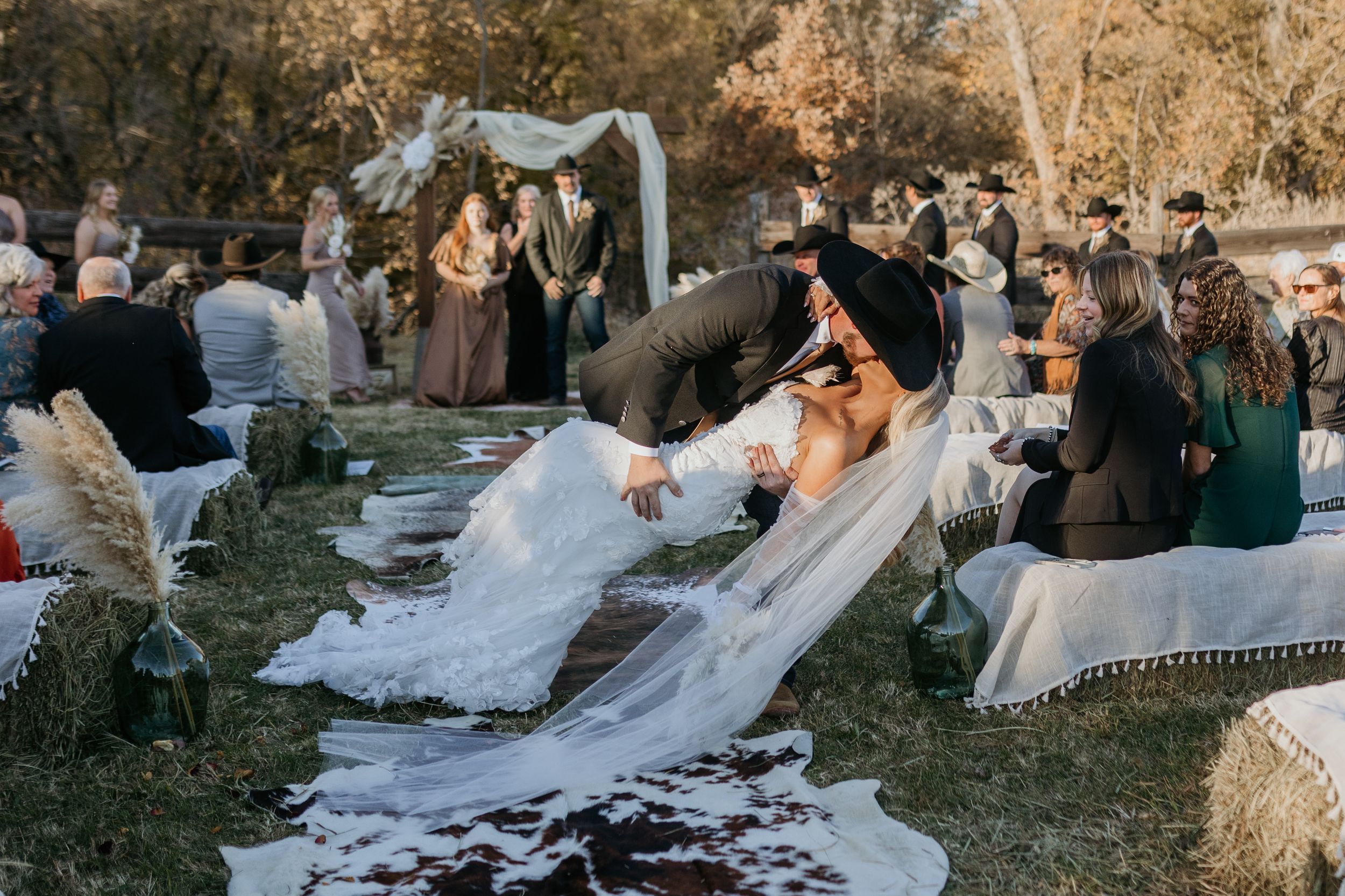 A candid moment at an outdoor wedding reception with guests sitting on picnic blankets during a fall afternoon celebration.