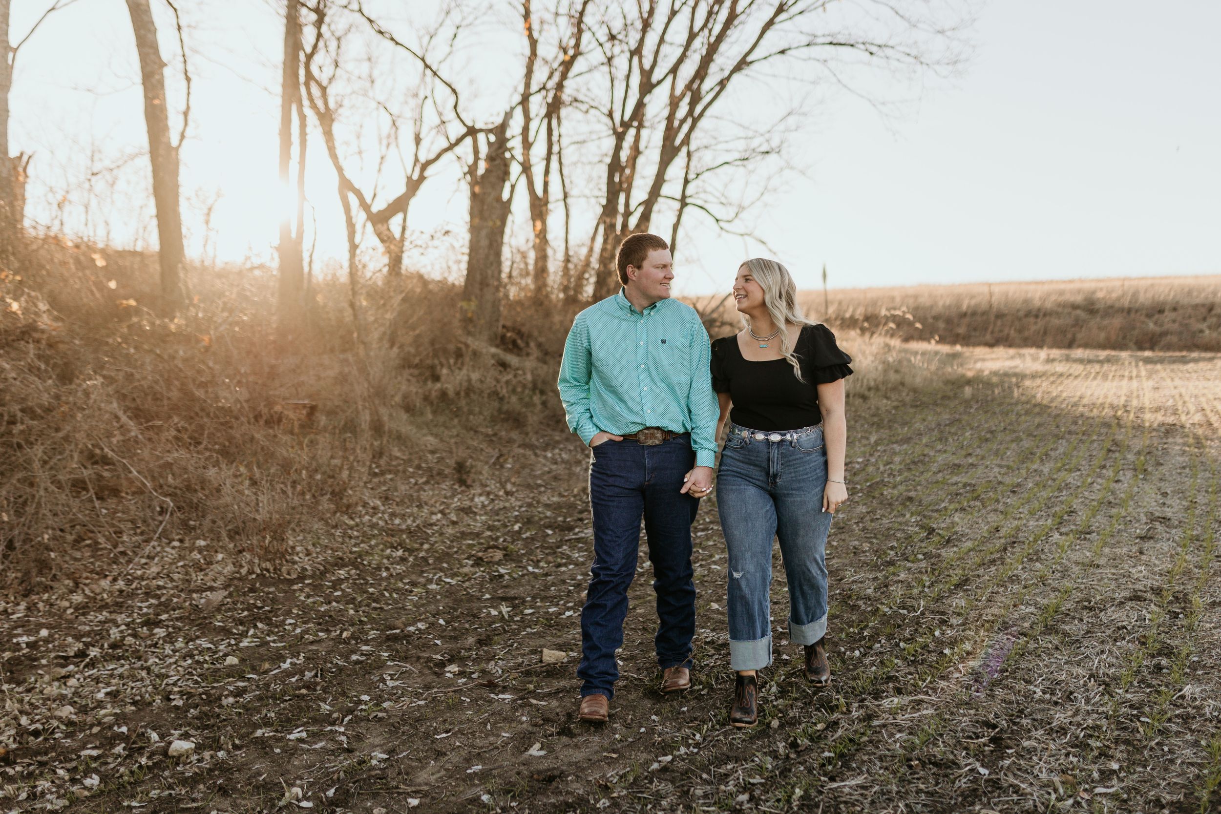 A couple walks together along a sunlit trail at golden hour during sunset.