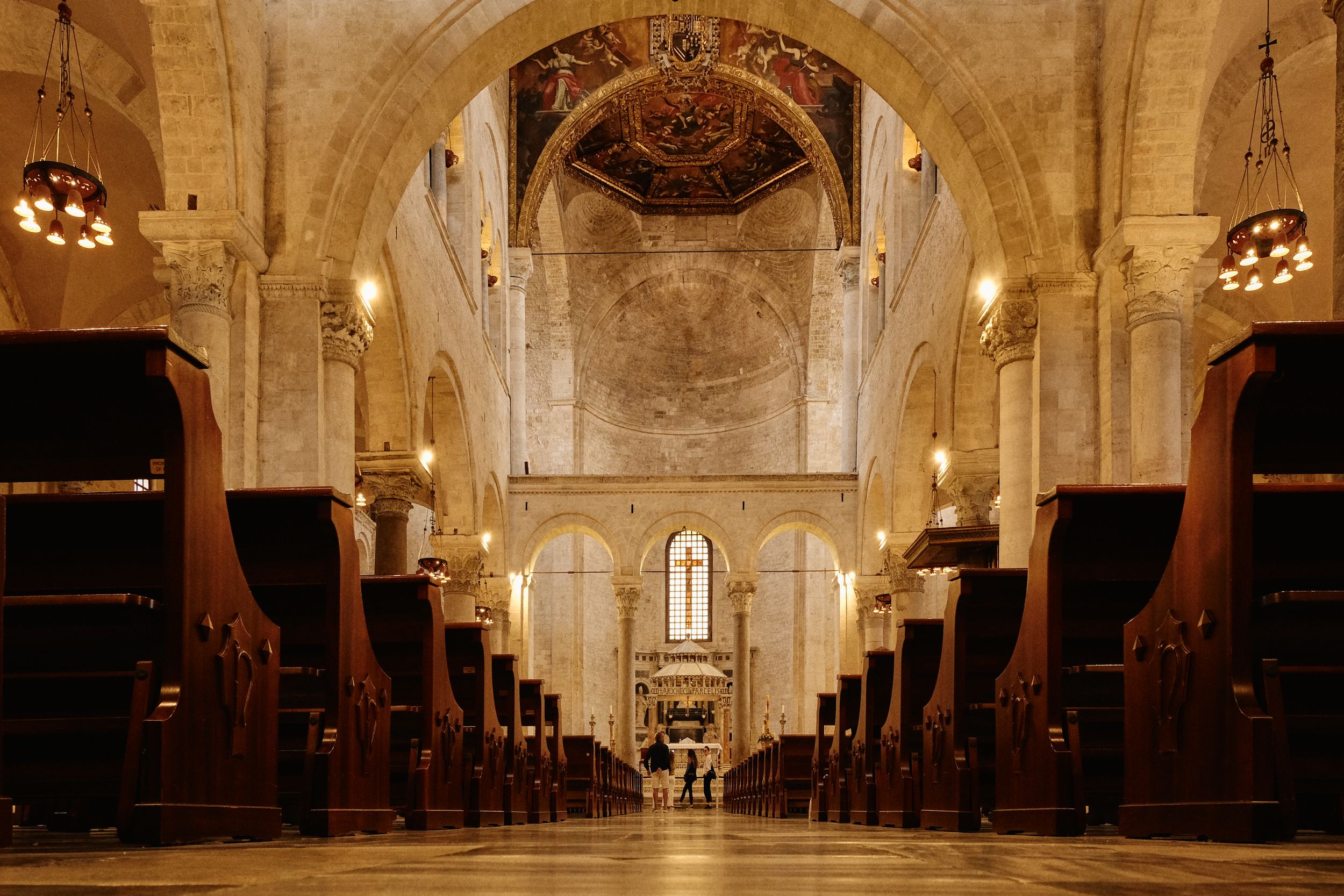 Interior of historic cathedral with wooden pews leading to altar under vaulted ceiling.
