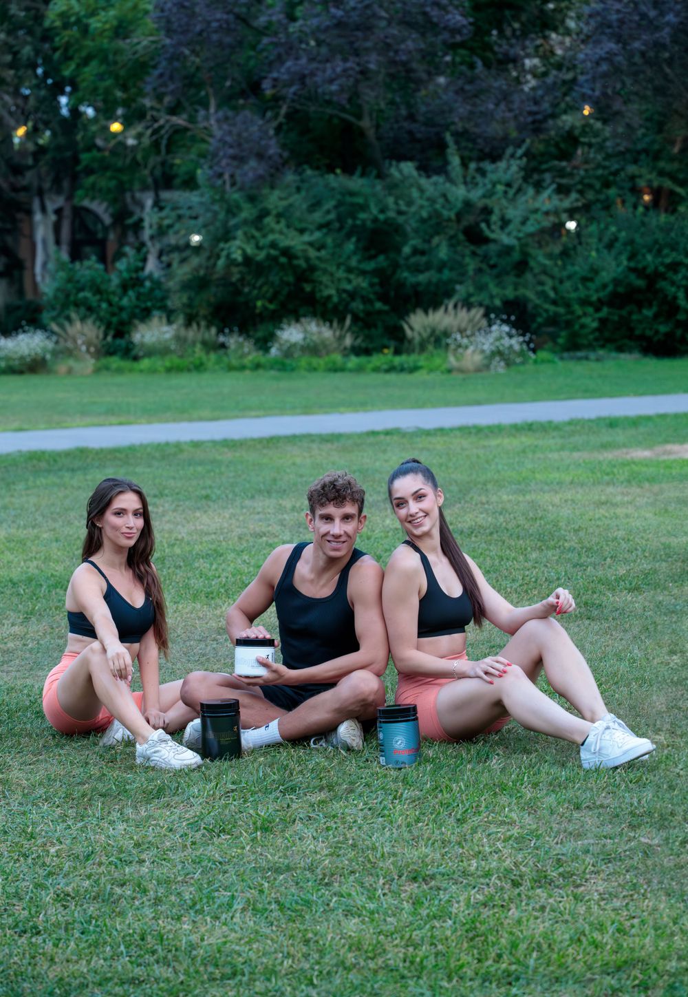 Group enjoying refreshments while sitting on grass during outdoor fitness break.