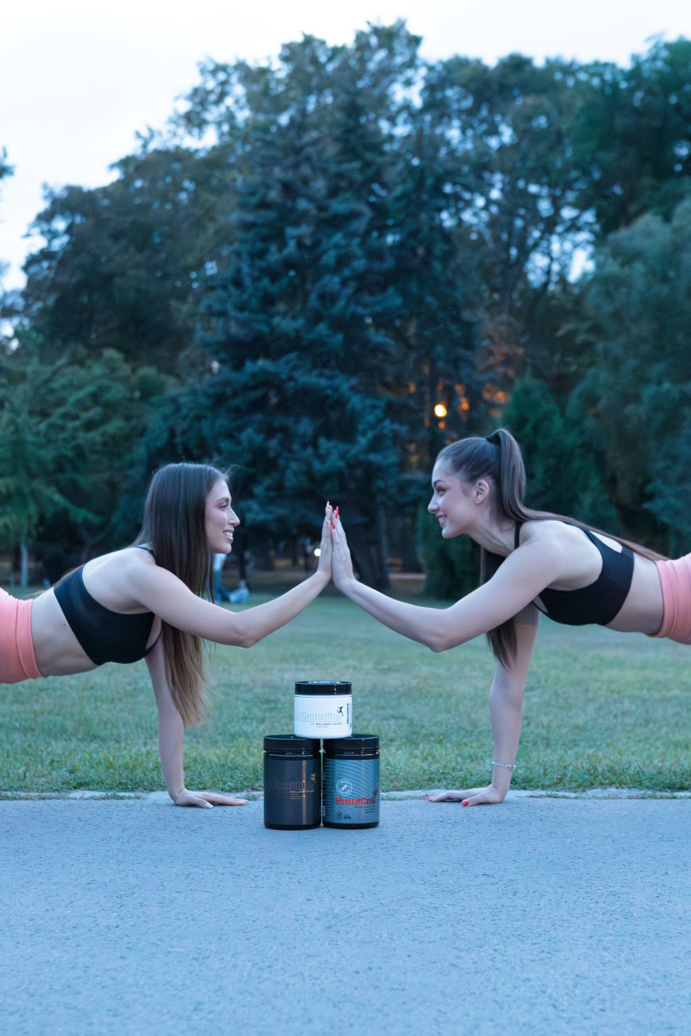 Two athletes doing planks and high-fiving with supplement containers between them.