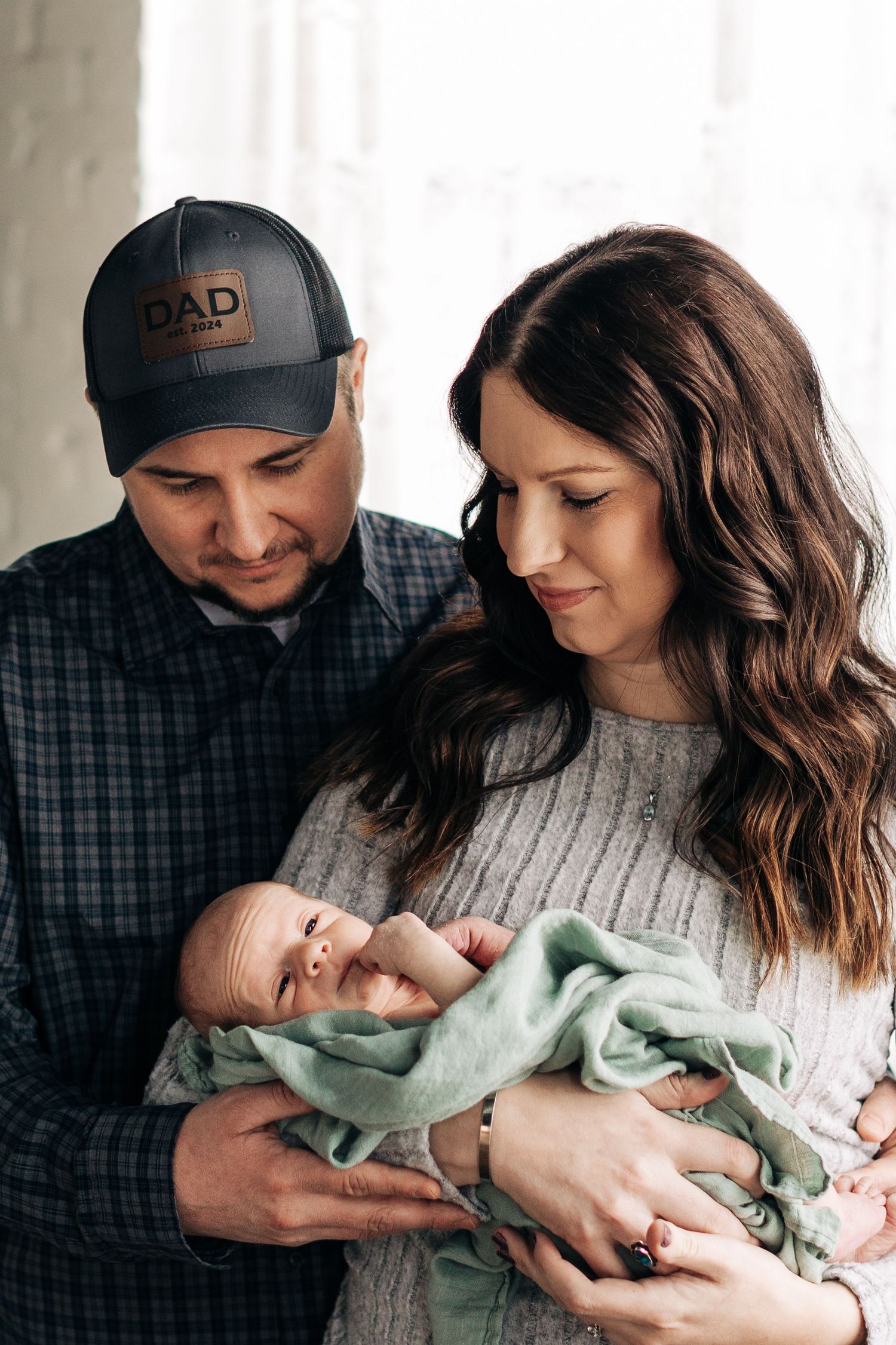 An intimate indoor family portrait with soft natural window lighting.