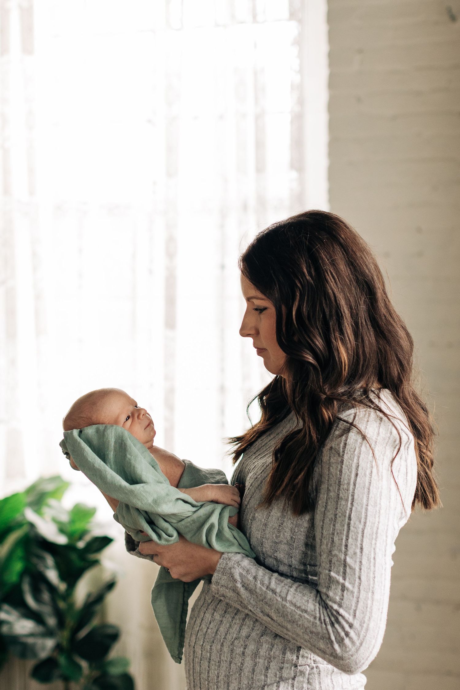 A tender moment captured by window light with soft interior decor.