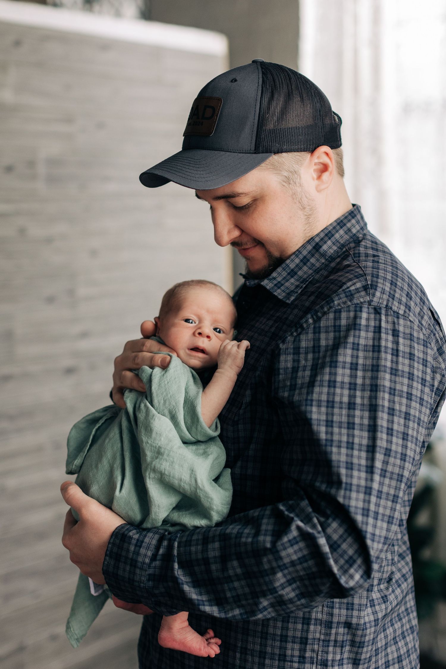 A touching moment captured in natural window light with plaid and sage green fabric.
