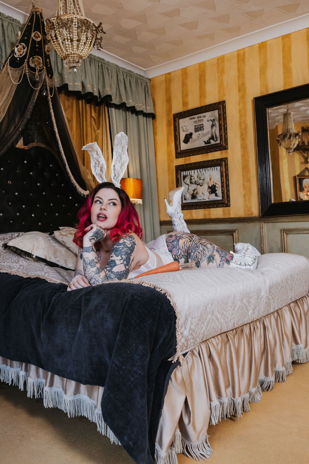 curvy tattooed model with pink hair is posing on a bed in white lingerie and bunny ears at Hotel Pelirocco in Brighton
