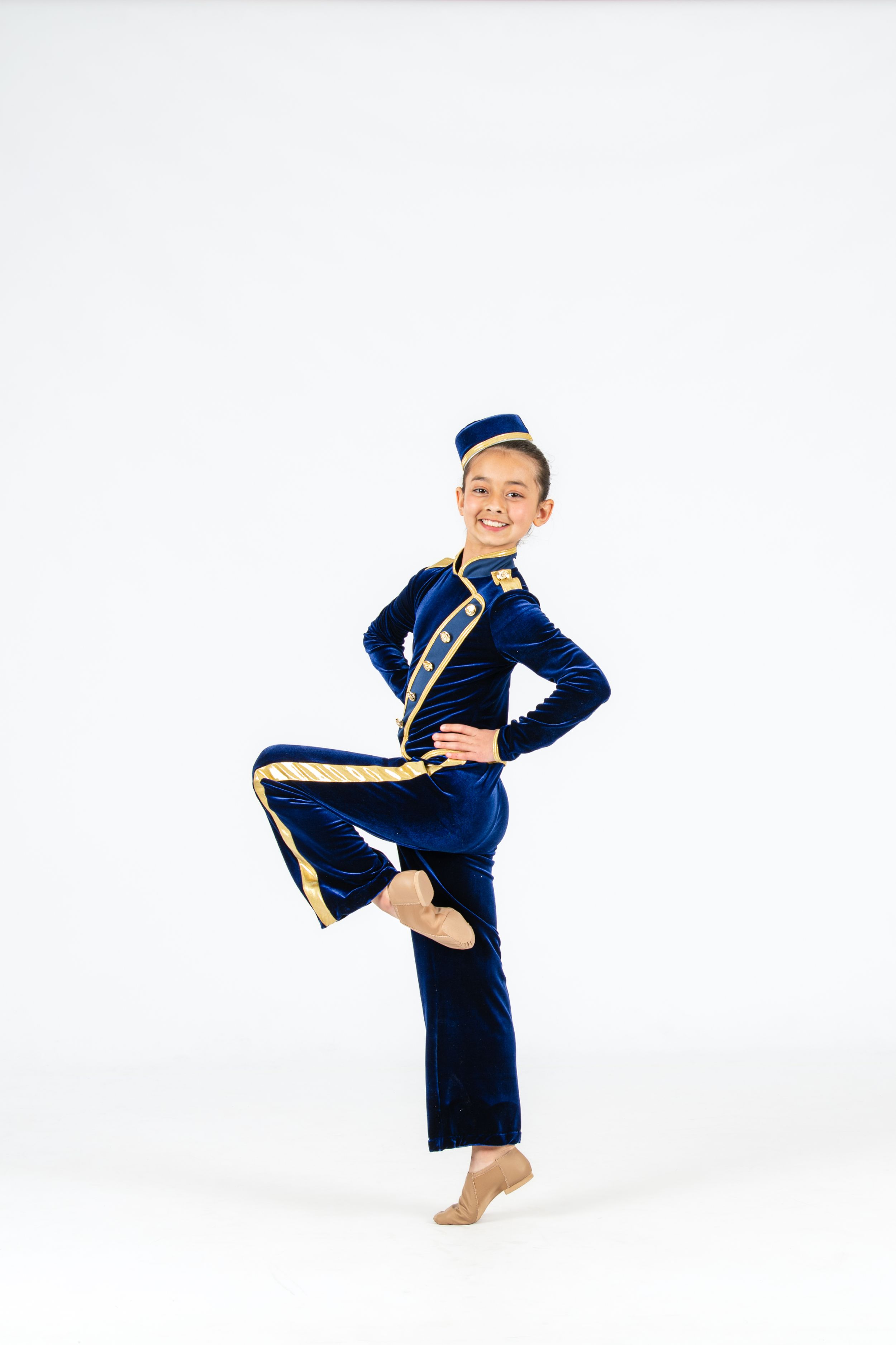 Performer in navy and gold marching band uniform strikes a pose against white background.