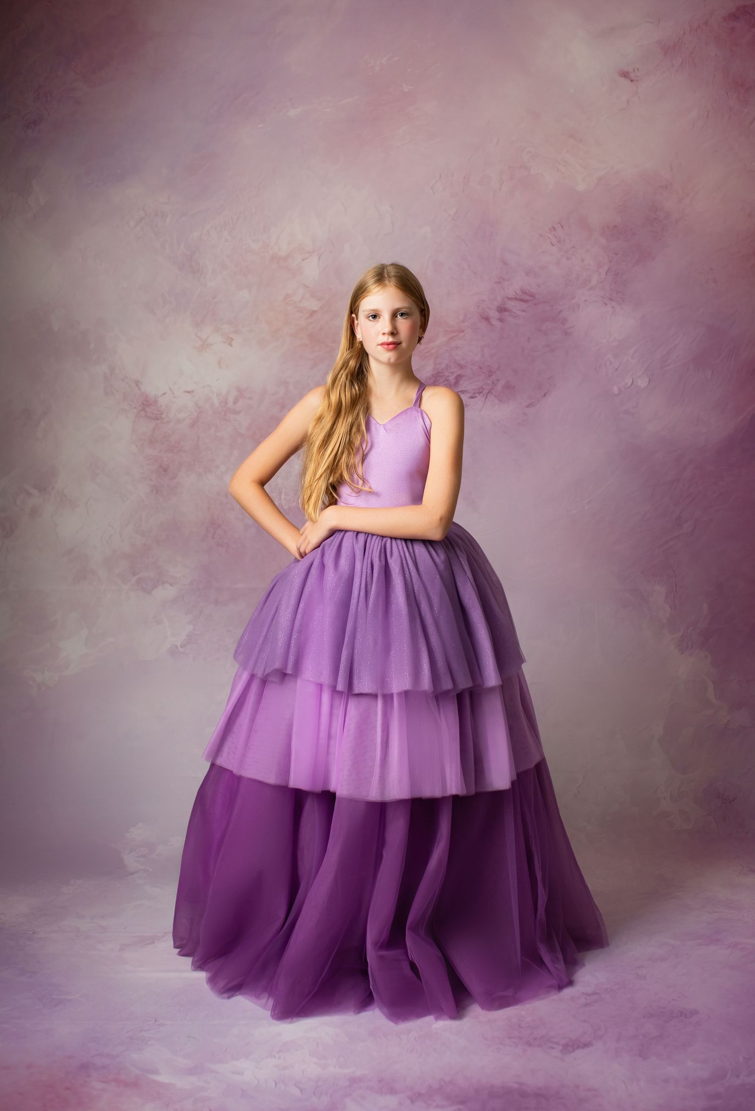Short lilac party dress with tulle skirt against floral backdrop with large purple satin bows.