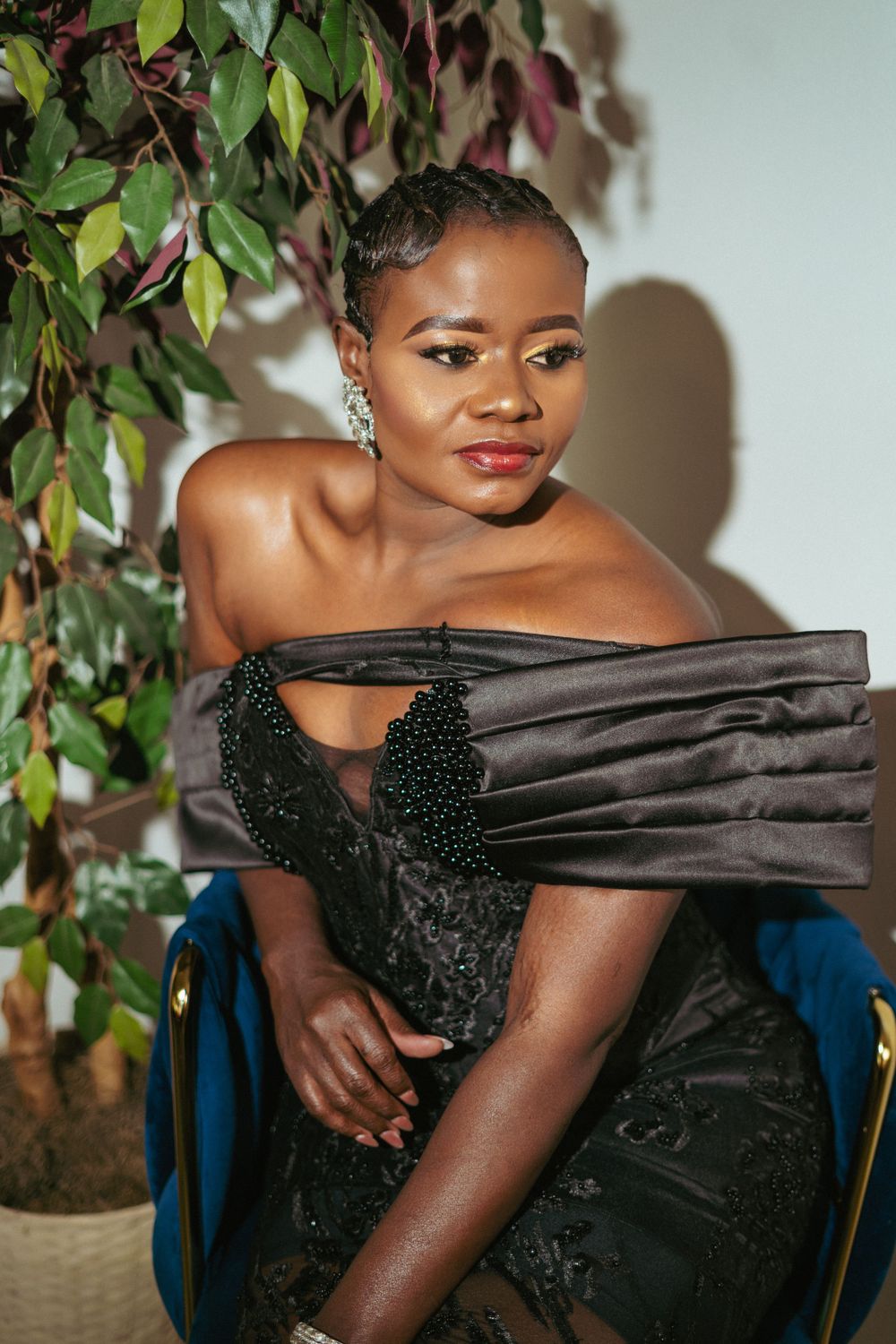 Sophisticated portrait in black dress with dramatic lighting and foliage backdrop.