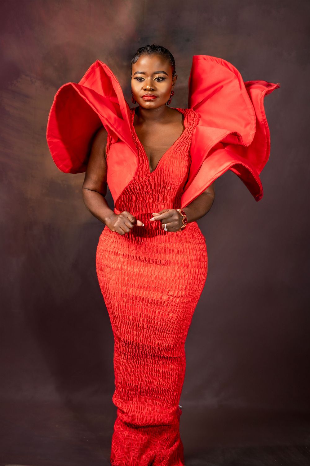 Dramatic fashion portrait in textured red gown with sculptural details.