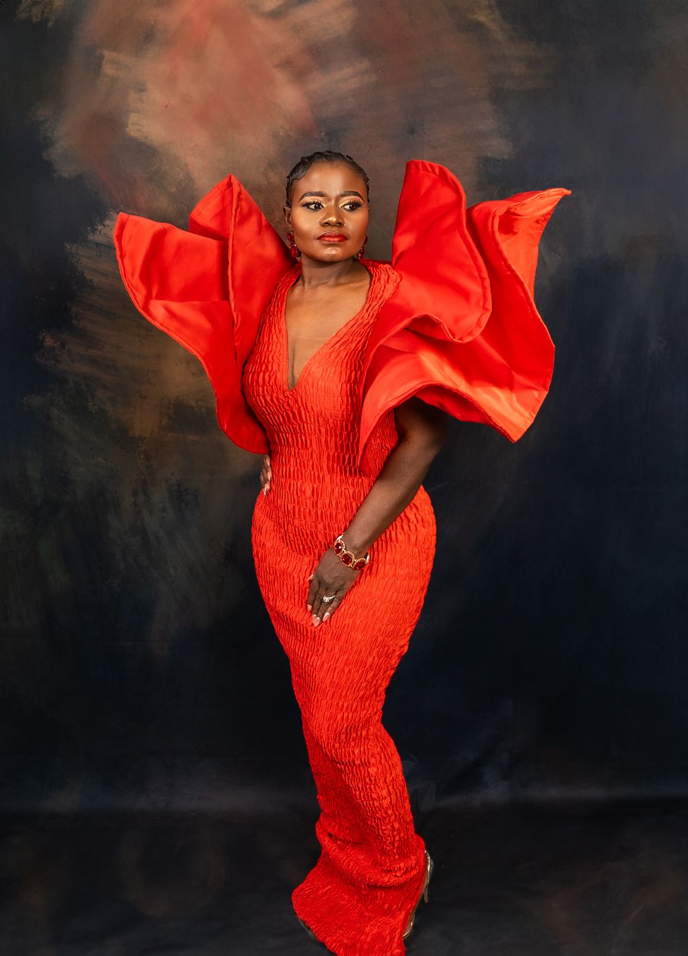 Dramatic fashion photograph of red form-fitting dress with statement sleeves against dark background.