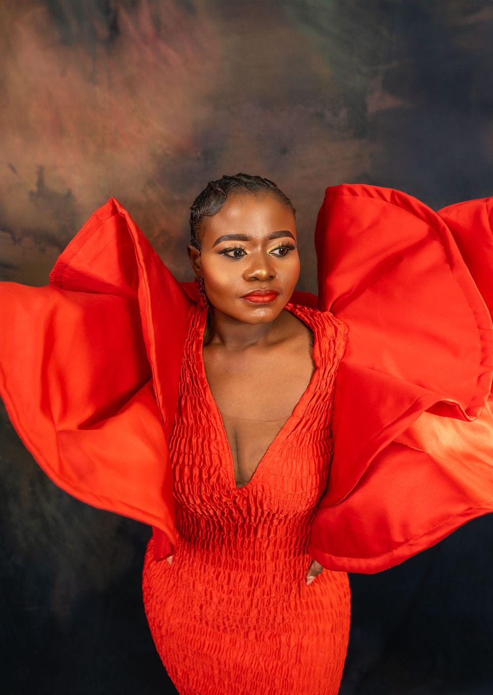 High fashion portrait featuring luxurious red dress with architectural sleeve details.