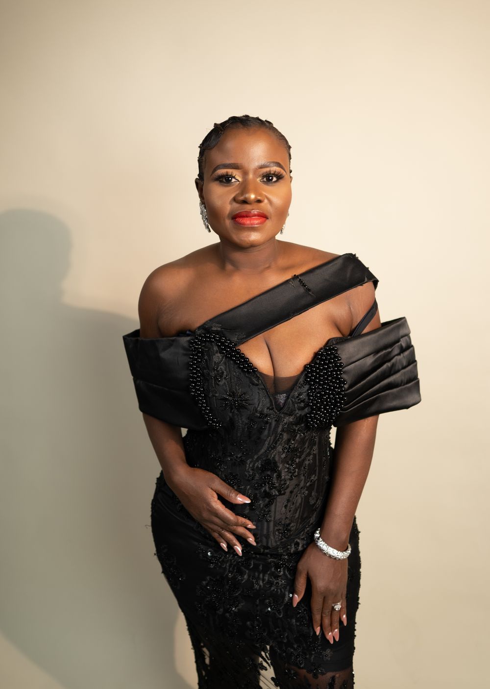 Close-up portrait showcasing black evening dress with pleated satin detail and bracelet accessory.