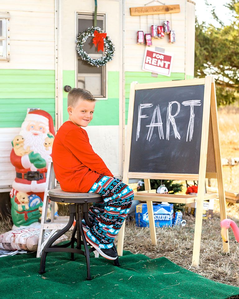 Humorous holiday scene with chalkboard reading 'FART' outside decorated vintage camper.