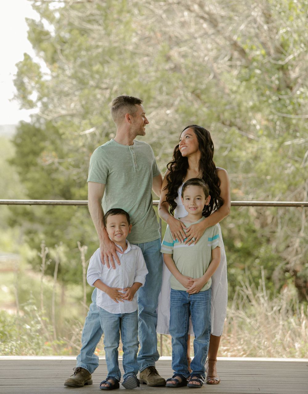 Family sitting together on wooden deck with natural scenery in background.