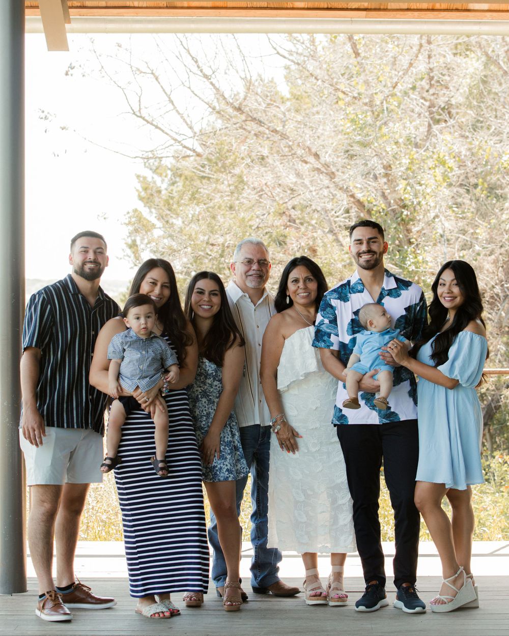 Large family group wearing coordinated blue and white outfits posing under covered porch.