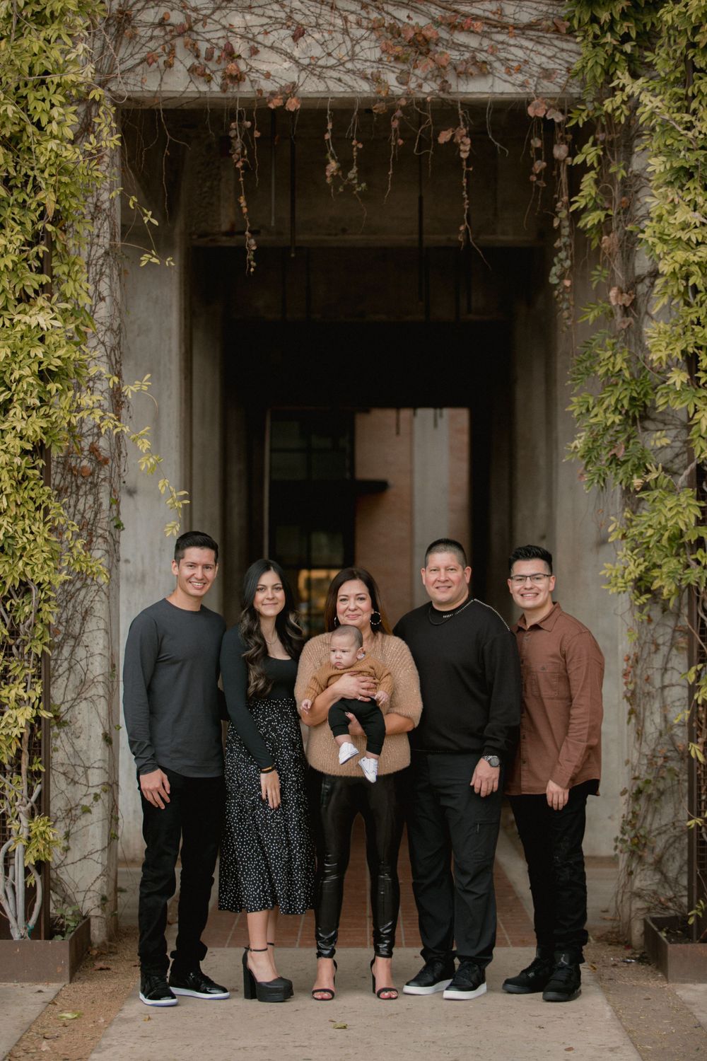 Family poses together in front of an ivy-covered stone archway wearing coordinated outfits.